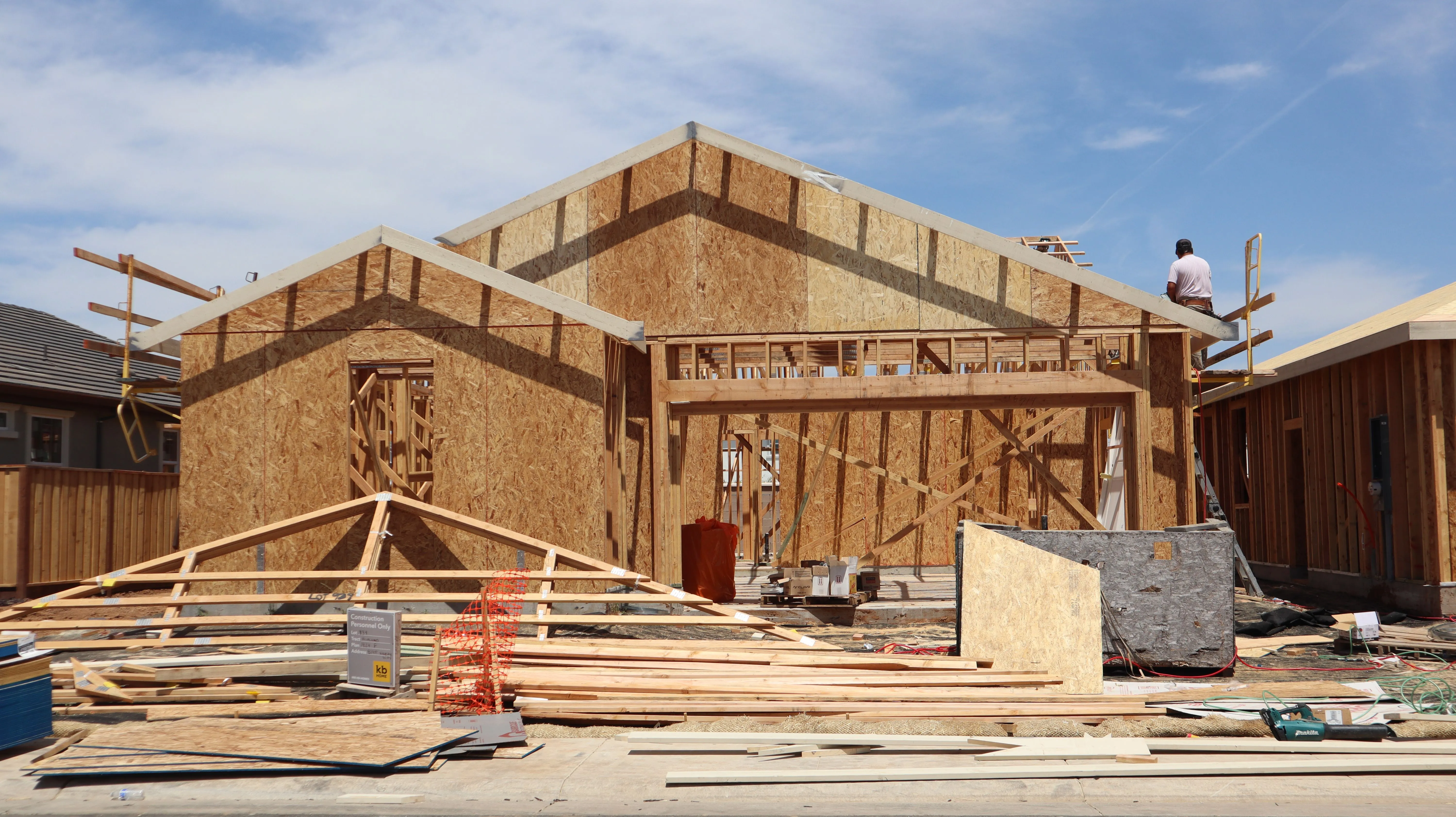 The timber frame and roof trusses of a new single-storey house going up under a blue sky