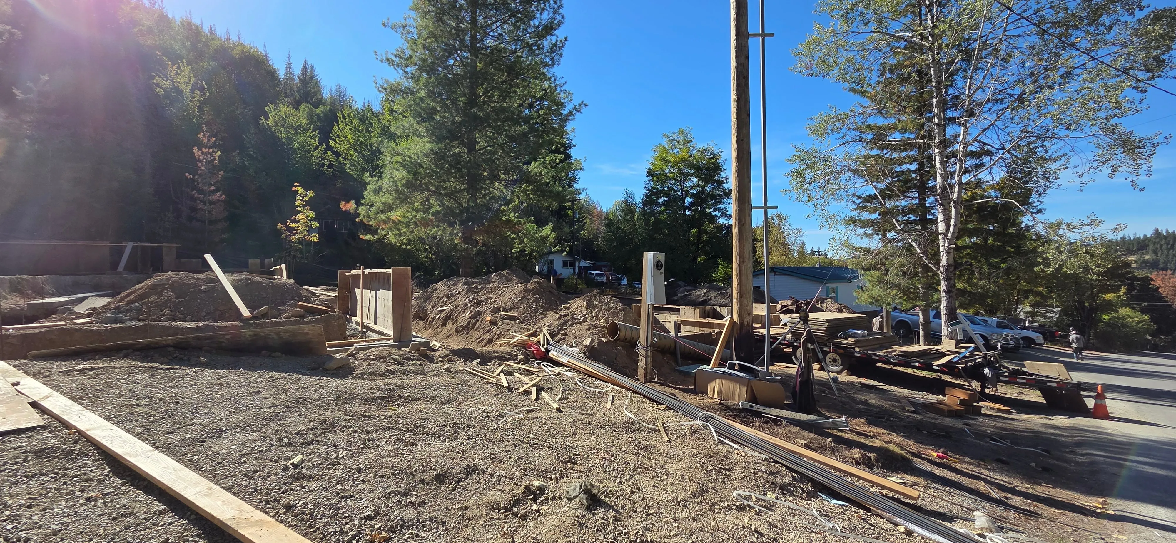 One of Jared's build sites: a cleared, graded lot with forms and lumber laid out, timbered hills behind it