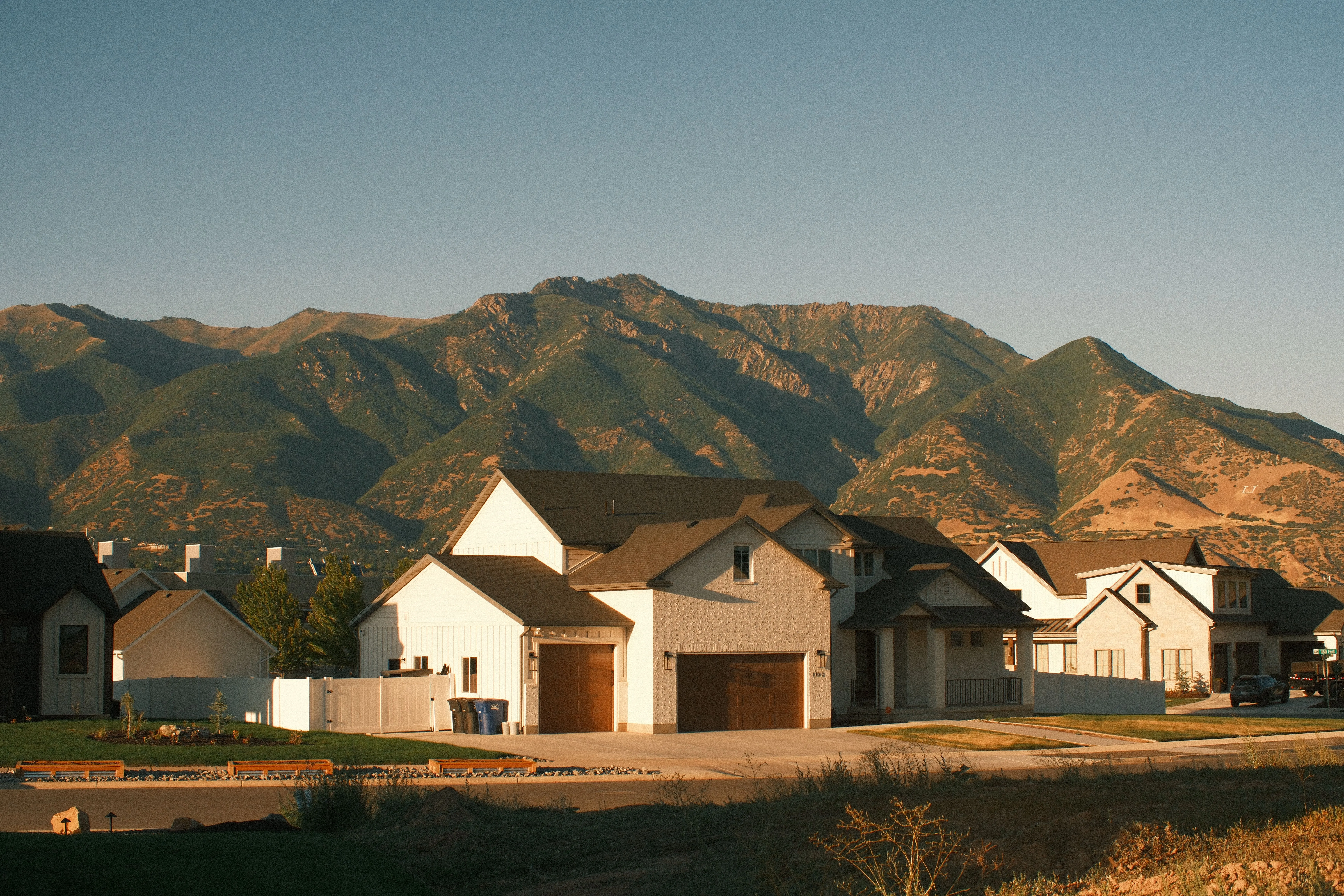 A row of newly built homes on a cleared site, mountain ridges rising behind them
