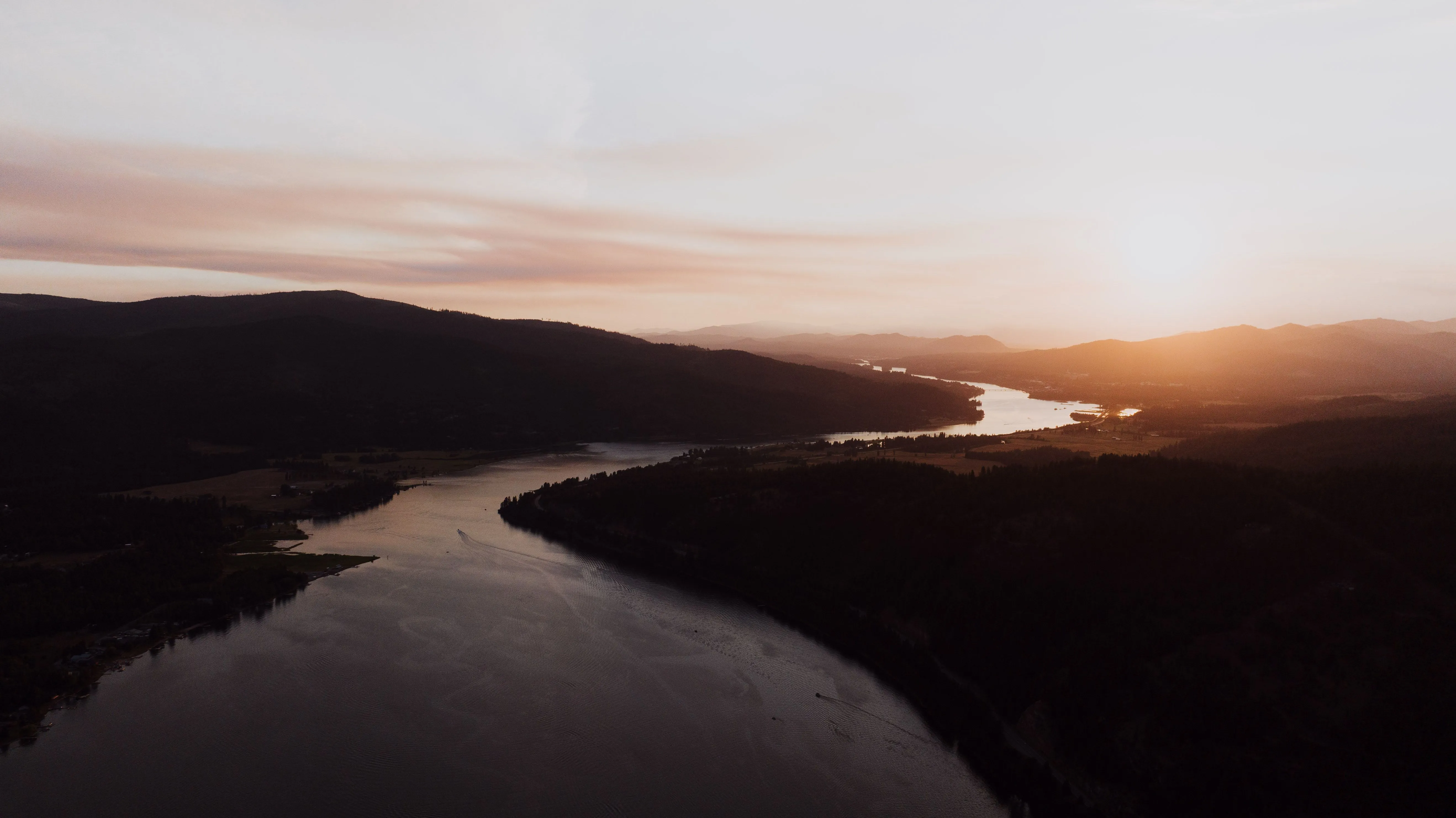 Aerial view of a river valley glowing orange at sunset in the Idaho panhandle