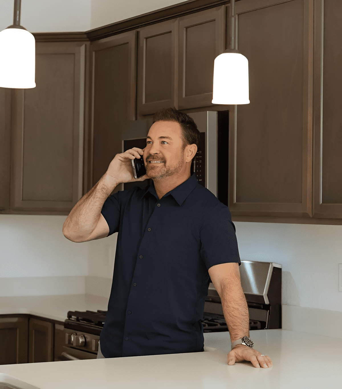 Man talking on phone in modern kitchen.