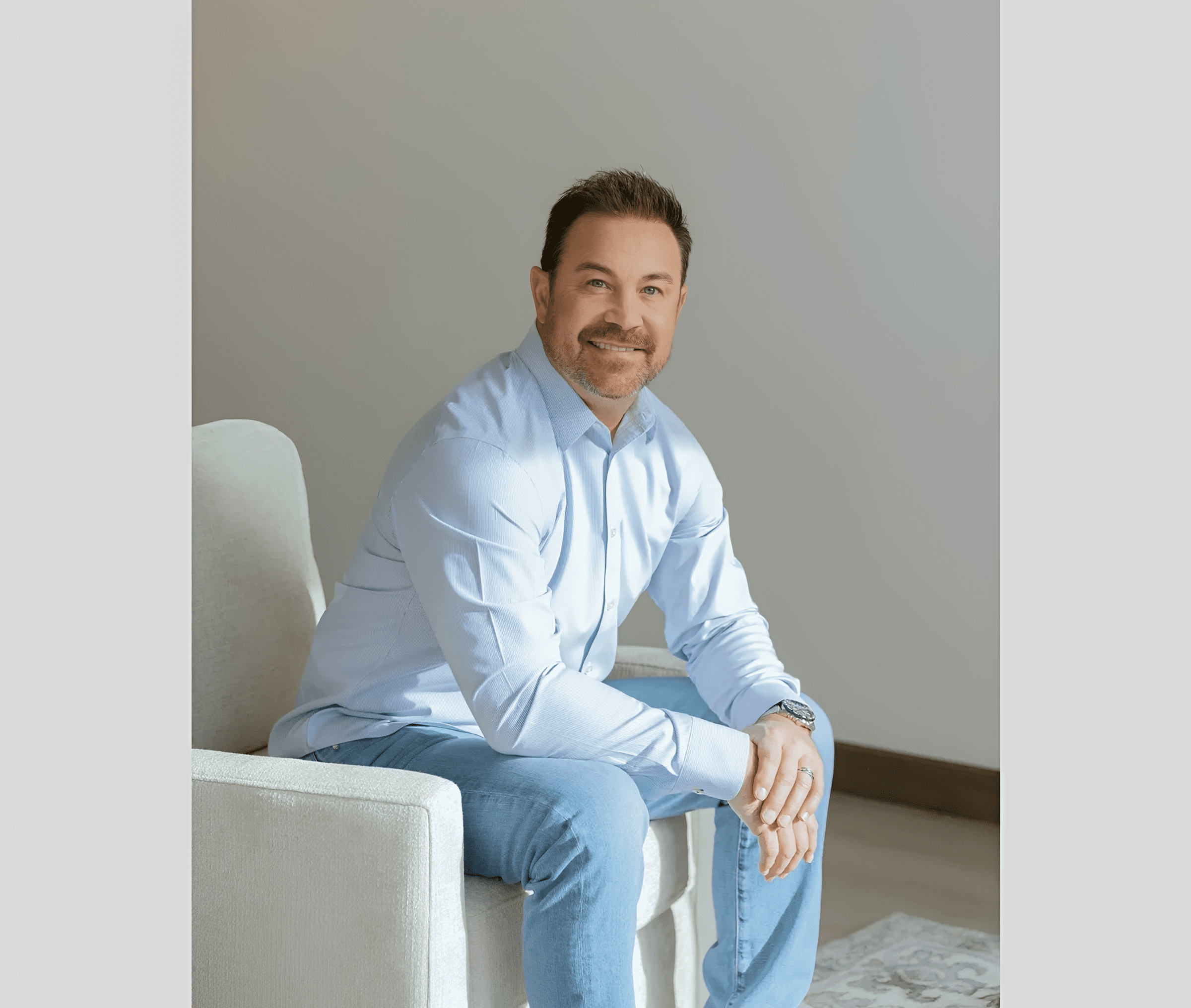 Man sitting on a chair, smiling confidently.